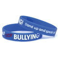 Two blue silicone wristbands with the text "STOP BULLYING!" and "Stand up and speak out" printed in white and red, designed to promote awareness and encourage an anti-bullying message. Product Name: 100 Pack - Anti-Bullying ½” Blue Silicone Wristband