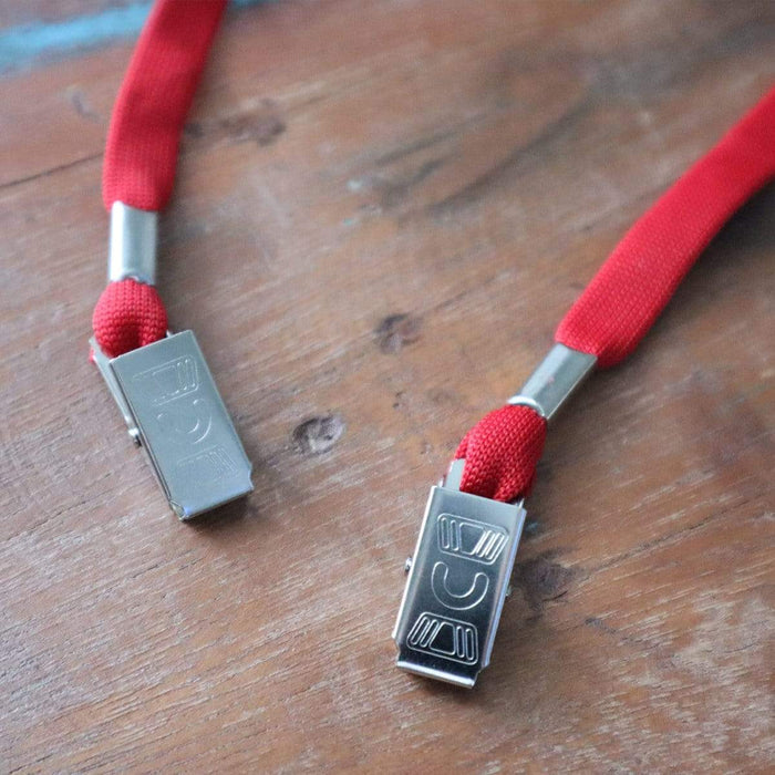 Close-up of two red 25 Pack Bulk Double-Ended Lanyards with Bulldog Clips on Each Side Assorted Colors with metal buckles lying on a wooden surface, resembling sturdy bulldog clips ready for action.