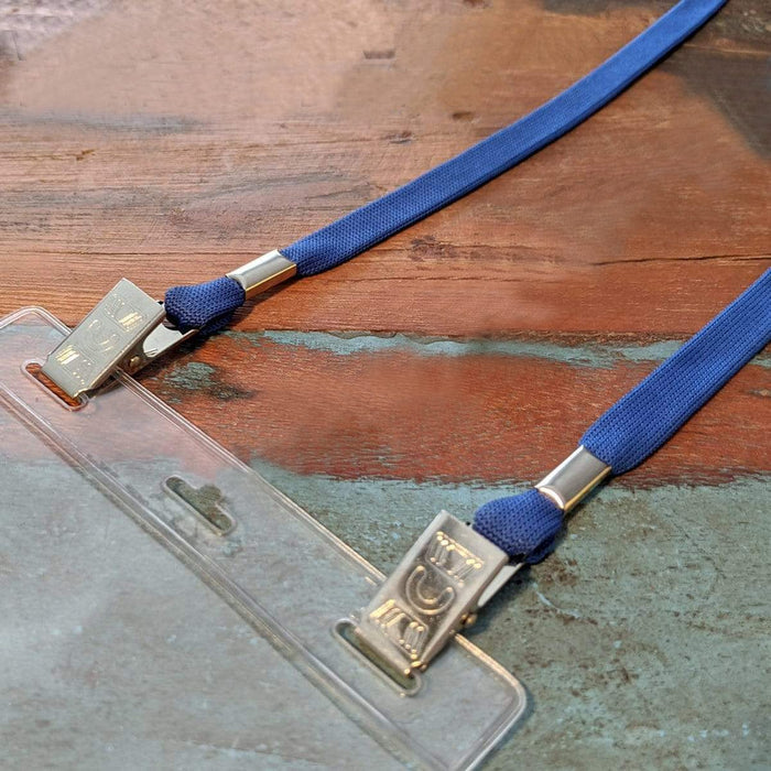 A close-up of a clear plastic ID badge holder with 25 Pack Bulk Double-Ended Lanyards with Bulldog Clips on Each Side Assorted Colors attached, resting on a wooden surface. Sold by Specialist ID.