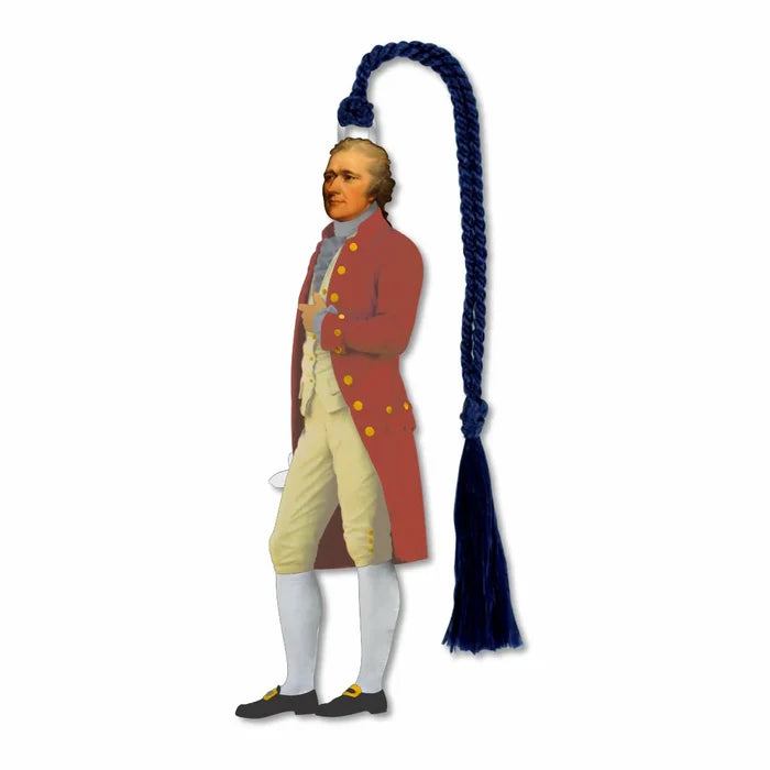 The image shows a small, die‑cut silver bookmark image of Alexander Hamilton standing upright. He wears a red coat with large yellow buttons, a light yellow vest and breeches, and a gray cravat. The bookmark is made of smooth, non‑tarnishing silver‑plated brass, feels firm and cool to the touch, and measures about 1 inch wide and 3.5 inches long. A blue silky cord with a tassel is attached at the top.