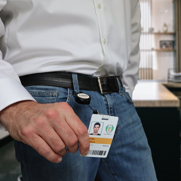 A person wearing a white shirt and blue jeans displays an ID badge clipped to their belt with a Custom Compact Key-Bak Retractable Carabiner ID Badge Reel with Key Ring and Your Logo for secure and easy access.