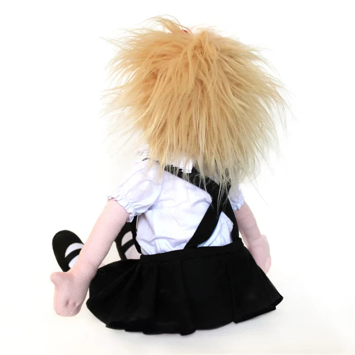 The image shows the doll seated with her back facing the viewer, her short blond hair tousled and playful. She wears Eloise’s iconic outfit—a ruffled white blouse, black pleated skirt, and satin black shoes.