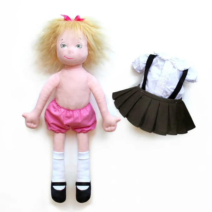 The image shows the 18‑inch Eloise doll dressed in pink bloomers, white socks, and black shoes, with her blond hair topped by a pink bow. Placed to the right of the doll are her removable outfit pieces—a white shirt and black skirt with suspenders—clearly shown off her body to illustrate that they can be easily taken on and off.