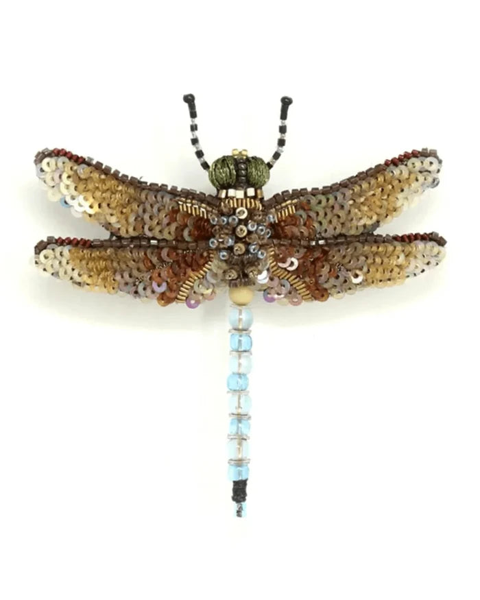 Emperor Dragonfly Brooch - A small dragonfly brooch with a long, slender body and four outstretched wings. The surface blends soft fabric with raised stitching, beads, and sequins, creating a lightly textured, shimmering finish in shades of yellow, beige, and brown, with a beaded tail in pale blue. The wings are thin, symmetrical, and delicately detailed. A smooth metal pin on the back allows for easy fastening, and each handmade piece shows slight variations in texture and sparkle.