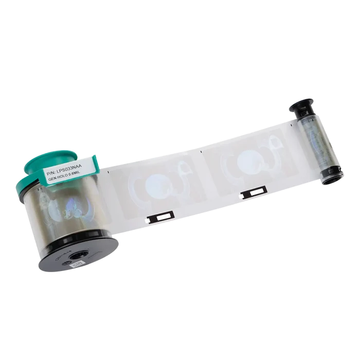 A film roll labeled with a green sticker, partially extended to reveal three black-and-white MRI brain scan images, resembling the Evolis LPS033NAA Generic Holo Patch Laminate - 600 Prints. It features black end caps on both sides and is compatible with Primacy2 and Avansia Lamination units.