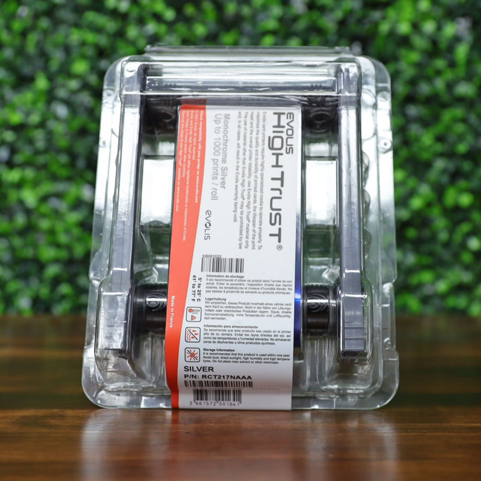 Angled view of the Evolis RCT217NAAA metallic silver monochrome ribbon in sealed blister pack, clearly showing the product label, red capacity strip, and barcode. Photographed and sold by Specialist ID, an authorized Evolis dealer.