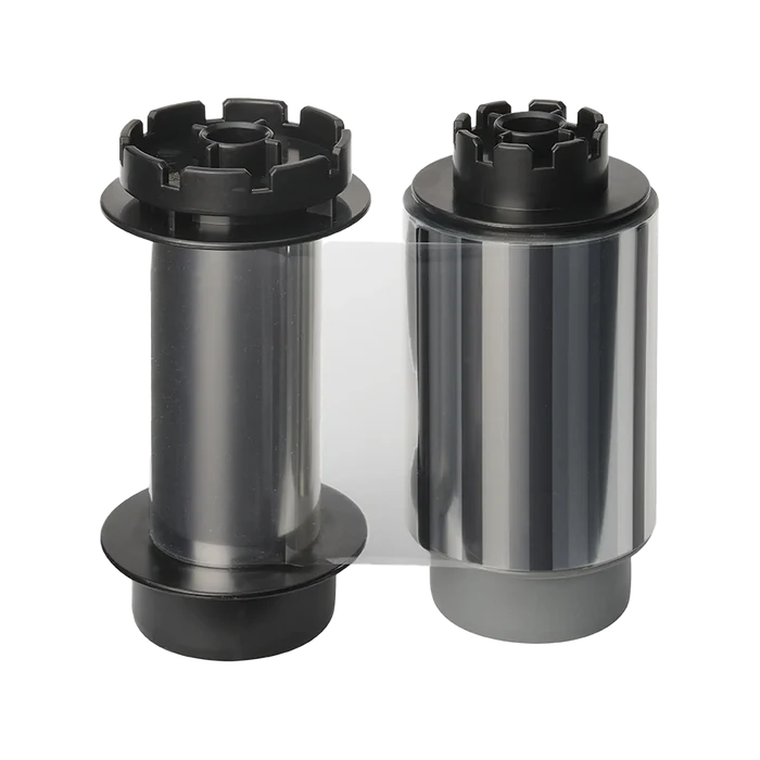 Two cylindrical rolls of film, one with a black and clear body and the other with a shiny silver body, both featuring black end caps, ideal for use with the Evolis RTCL009NAA Clear Transfer Ribbon - 500 Prints, compatible with Avansia Retransfer ID Card Printers.  Sold by Specialist ID, an authorized Evolis dealer.