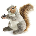 A soft, lifelike gray squirrel hand puppet with fuzzy mixed‑color fur, a movable mouth, poseable head and arms, delicate thread whiskers, and a tiny plush acorn held in its paws.