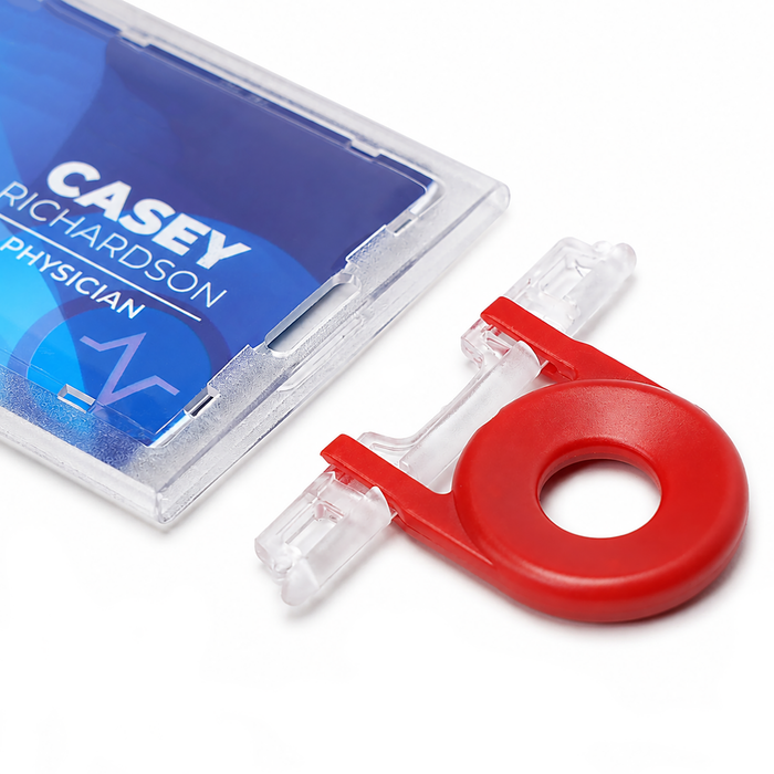 A close-up of a blue physician ID badge labeled "Casey Richardson" next to a red and clear retractable holder, featuring the Guard Key For Locking Card Holder (P/N 1840-6615) for enhanced security.