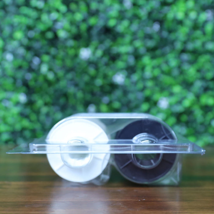 Bottom view of the HID Fargo 82603 PolyGuard overlaminate ribbon showing black and white ribbon spools in sealed blister packaging. Photographed and sold by Specialist ID, an authorized Fargo dealer.