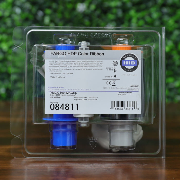 Close-up of HID Fargo 84811 YMCK color ribbon in clamshell packaging with visible part number, barcode, expiration date, and “Genuine HID” label. Shows ribbon compatibility with HDP8500 printer and 500-image yield. Photographed and sold by Specialist ID, an authorized HID Fargo dealer.
