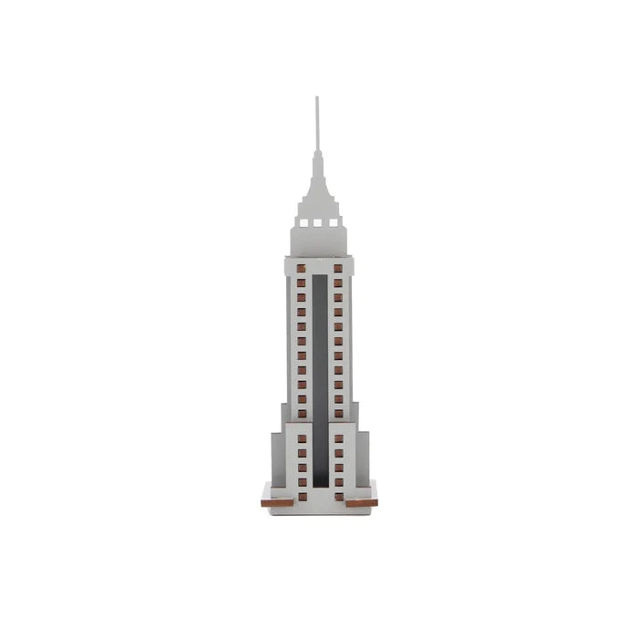 A small, upright laser‑cut wooden model of the Empire State Building in gray, with red square cutouts representing its windows.