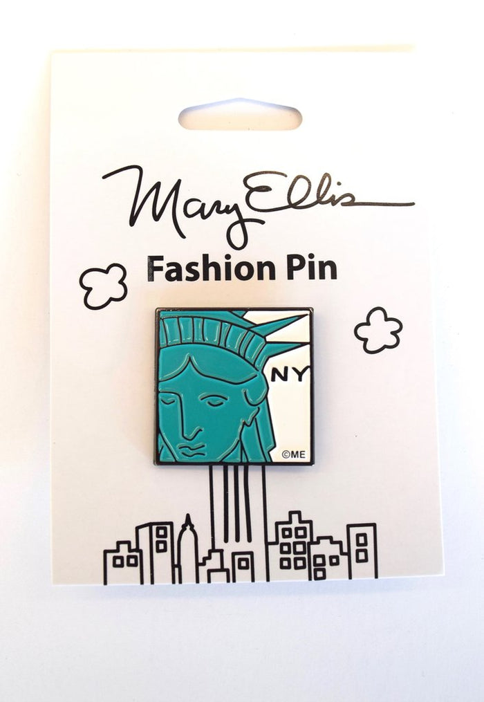 Statue of Liberty Pin:
A simplified, graphic illustration showing a partial view of the face and crown, rendered in bright green with clean, bold outlines and minimal interior detail. The image is immediately recognizable and presented in a flat, iconic style rather than a realistic one. The letters “NY” appear in black to the right of the illustration, set against a white background. The item is shown in its clean illustrated white packaging.