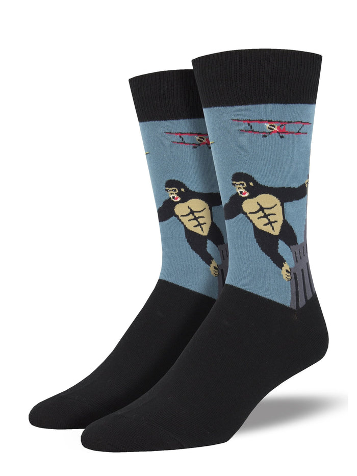 These are crew‑style socks featuring a classic New York City movie scene. The design shows King Kong, a black‑and‑white ape, with his arms outstretched as he clings to the gray Empire State Building. A small red bi‑plane appears nearby as if attacking, set against a light blue background.

The top band and foot of the socks are black. Made from a soft cotton‑nylon blend, the socks offer gentle stretch and detailed imagery, making them a fun and memorable New York City souvenir.
Sock size 10-13 fits U.S. men