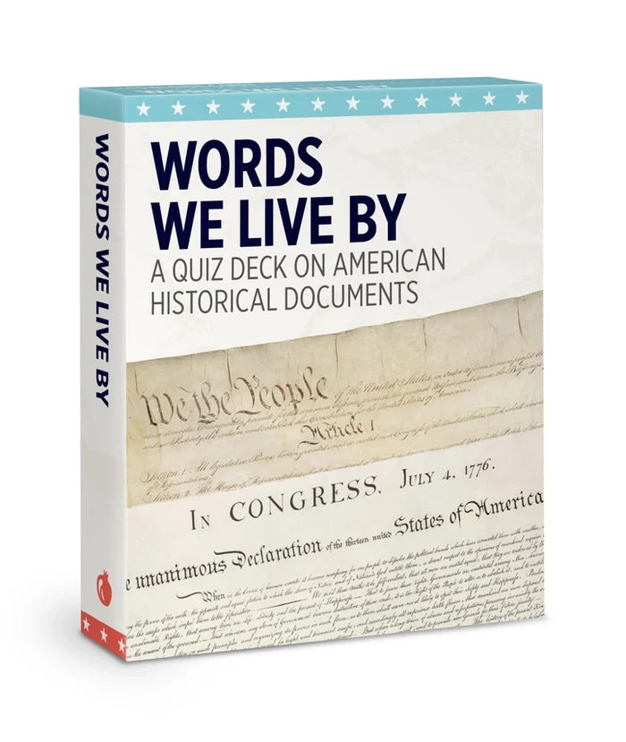 The image shows quiz deck packaging titled “Words We Live By” on a white background. The small, sturdy box—about the size of playing cards—holds 48 thick cards with quotes on one side and explanations on the other. Designed in warm parchment beige and soft ivory, the cover evokes the Declaration of Independence with black text and subtle brown accents, creating a classic, museum‑style look.