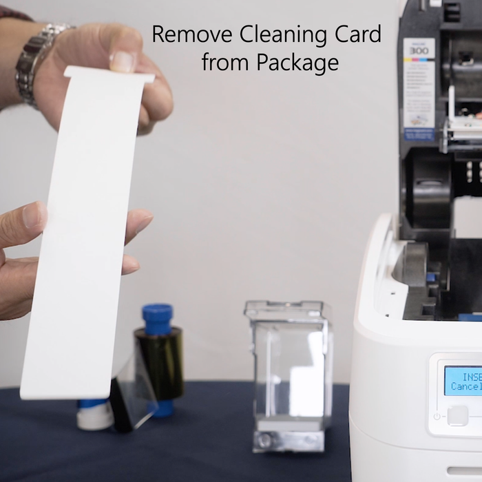 Person holding a white cleaning card with text 'Remove Cleaning Card from Package' above a printer. Sold by Specialist ID.