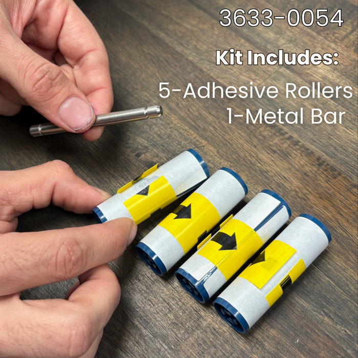 A hand holds a Magicard 3633-0054 Cleaning Roller Kit with Metal Bar (5 Pack) on a wood surface, showing 1 metal bar and 5 adhesive rollers—perfect for maintaining your Magicard ID card printer.