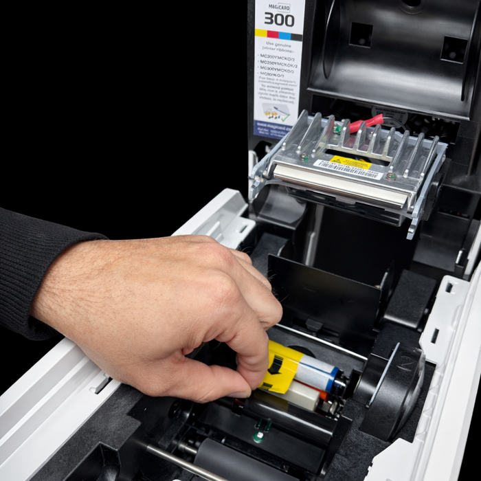 A hand loads the Magicard 3633-0054 Cleaning Roller Kit into a printer, aligning it precisely to protect the printhead and prevent card defects—just as accurate CSS box-sizing ensures flawless product page displays.