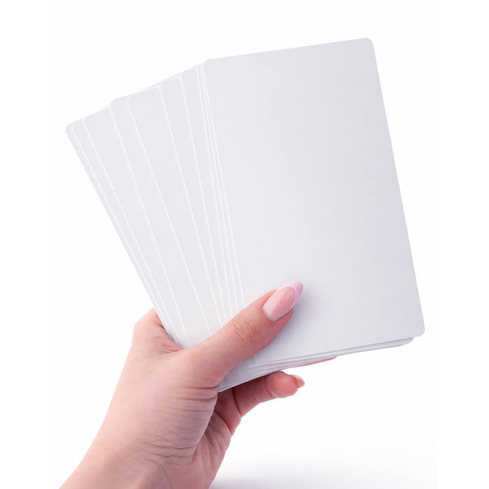 A hand holding a fanned-out stack of blank white cards against a white background, perfect for showcasing the results after using the Magicard E9887 Cleaning Kit for the Magicard Prima 8 ID Card Printer.