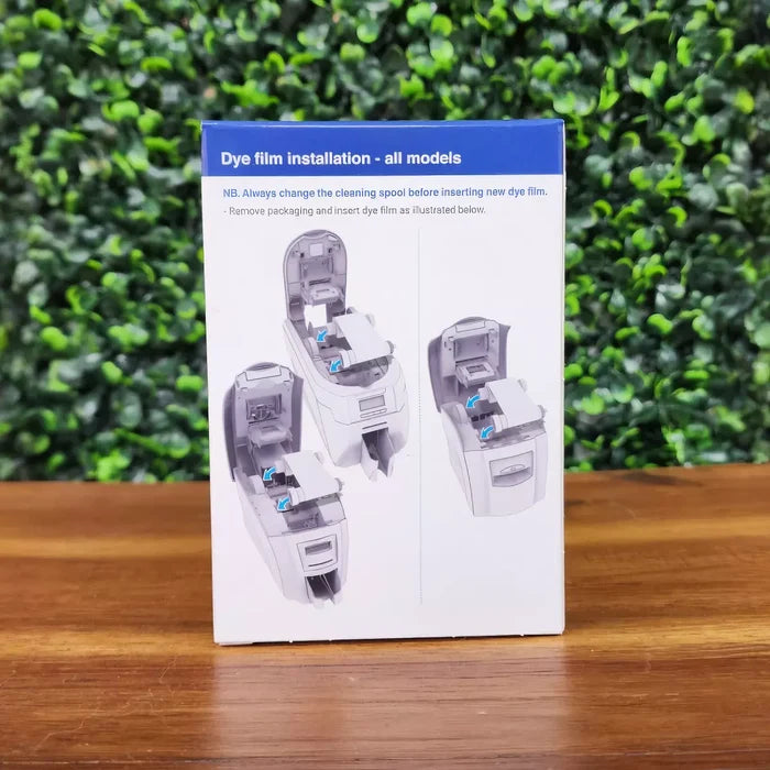 Box features illustrated, step-by-step instructions for installing the Magicard MA1000K-Black Monochrome K Ribbon (1000 Prints) in ID card printers, set against a leafy green background—ideal for easy ribbon installation.