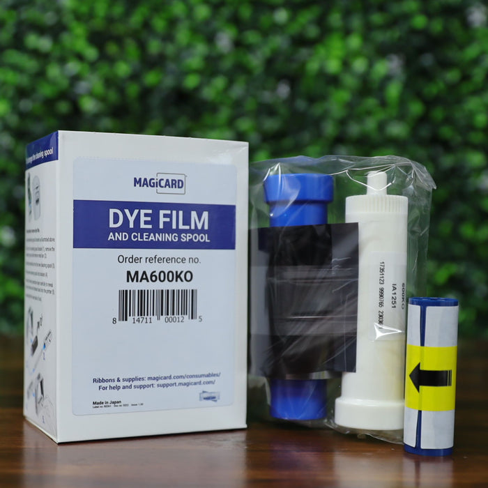 Magicard MA600KO printer ribbon with included cleaning spool and adhesive roller, shown next to retail packaging with barcode and product reference. Photographed and sold by Specialist ID, an authorized Magicard dealer.