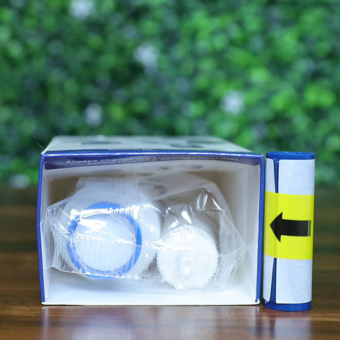 Top-down view of the Magicard PR1000W white monochrome ribbon partially inserted in its original box, showing the blue gear spindle and white cleaning spool inside a clear plastic bag. Includes yellow arrow installation guide on separate component. Photographed and sold by Specialist ID, an authorized Magicard dealer.
