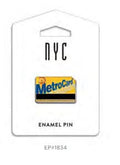 This MetroCard enamel pin is displayed on flat white packaging featuring “NYC”, an image of the pin, and the text “ENAMEL PIN” at the bottom. The pin itself is a small, rounded rectangle measuring about 1.25 by 0.8 inches, echoing the look of a real MetroCard. It showcases bright yellow enamel set in warm gold tone metal, with raised “MetroCard” lettering, a black swipe strip along the bottom, and a small raised MTA logo. The smooth metal back includes two secure pin posts for easy wear.
