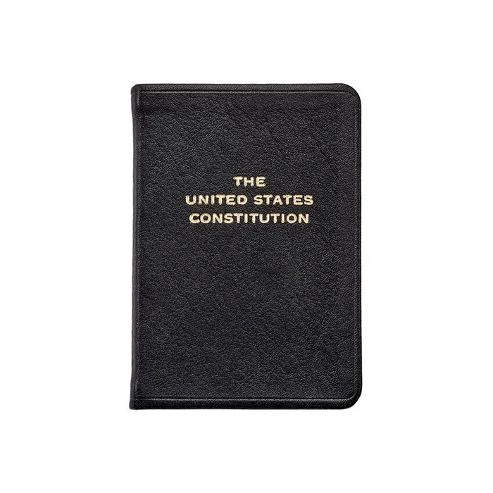 A black, leather‑bound book titled The United States Constitution, with the title stamped in gold lettering, shown against a clean white background.