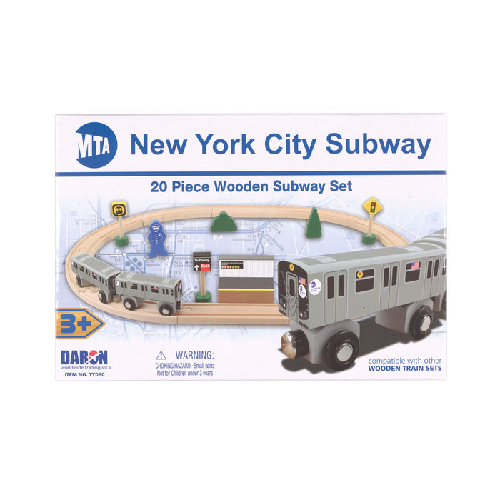 The image shows the package for the New York City Subway 20‑Piece Wooden Subway Set. On the front of the box, the set’s pieces are shown as they would look when arranged for play: two subway cars, wooden tracks, a platform, a conductor figure, trees, and several signal signs. In the lower right corner of the package design, there is a close‑up image of a silver‑gray train car with black wheels, silver rims, and a front connector.