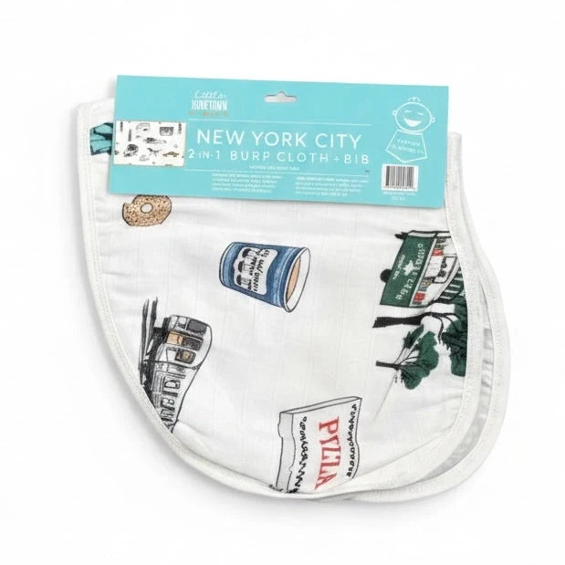 Featured against a white background is the NYC Burp Cloth and Bib Combo in white, decorated with illustrations of iconic New York items, including a blue Greek coffee cup, a black-and-white subway car sketch, a pizza box, a sesame bagel, and a green food cart. At the top, a header card displays the product title, “New York City 2-in-1 Burp Cloth + Bib,” along with a die-cut hole for hanging on retail display pegs.