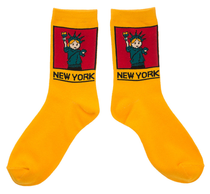 NYC Cartoon Statue of Liberty Socks 
These yellow crew socks feature a soft, woven cartoon image of the Statue of Liberty. On the ankle is a square red panel outlined in black, containing a friendly aqua-green Lady Liberty with small orange details in her hair and torch flame. Below the panel, “NEW YORK” appears in large, bold lettering in black. The socks feel smooth and flexible, made for comfortable everyday wear with playful New York character.