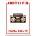 An enamel pin shaped like a 1980s boombox. It is primarily black with gold and red accents. Two large, round speakers sit on either side, with detailed cassette player buttons and controls in the center.