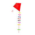 The image shows a classic, bright red diamond shaped kite with flowing multi color ribbon tails that add movement. The kite string is neatly looped around a matching red handle, all set against a clean white background.