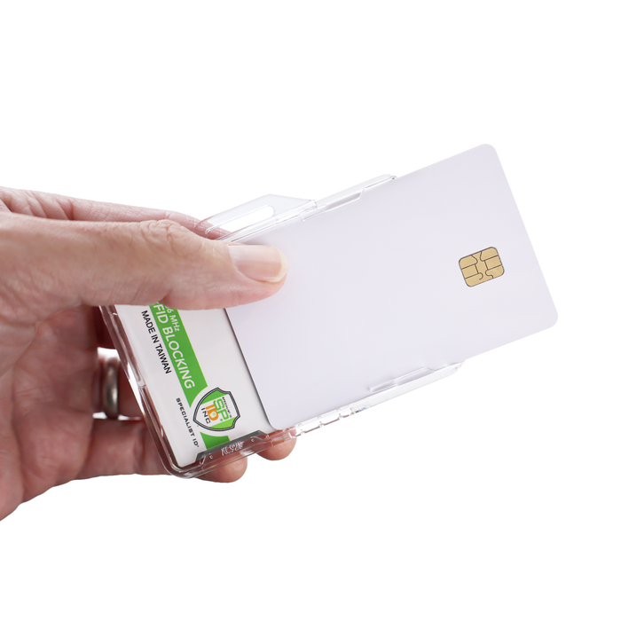 A hand holds the Specialist ID Dual Sided RFID Blocking Badge Holder (SPID-1760), a heavy-duty, transparent case for CAC, TWIC, PIV, HSPD-12 & Secure ID badges. It contains a white smart card with a gold chip and features an RFID blocking label.