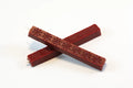 The image shows two 4‑inch burgundy wax sticks on a white background. The wax appears hard and smooth, with subtle daisy‑like embossed patterns. When melted, it becomes thick and pliable, then cools to a slightly flexible, buttery finish designed to resist cracking in the mail.