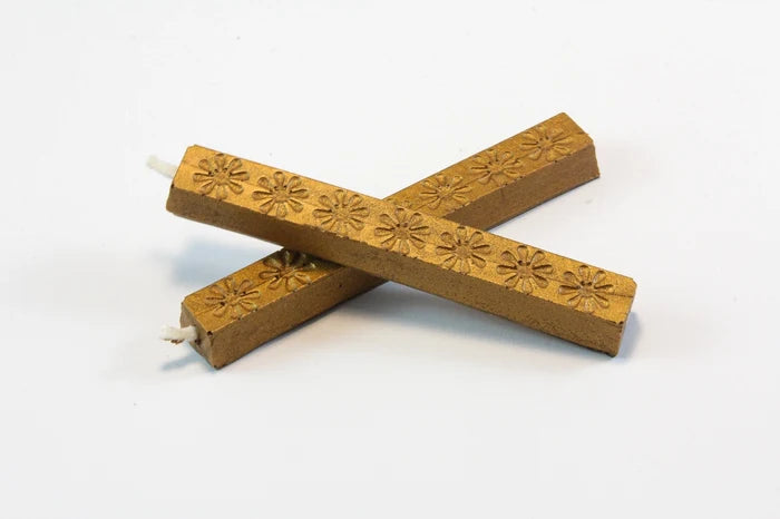 The image shows two 4‑inch dark antique gold wax sticks on a white background, with an aged bronze look. The wax feels hard and smooth, with subtle daisy‑like embossed patterns. When melted, it becomes thick and pliable, then cools to a slightly flexible, buttery finish designed to resist cracking in the mail.