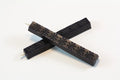 The image shows two 4‑inch dark blue wax sticks on a white background. The wax appears hard and smooth, with subtle daisy‑like embossed patterns. When melted, it becomes thick and pliable, then cools to a slightly flexible, buttery finish designed to resist cracking in the mail.