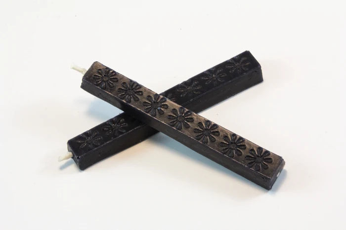 The image shows two 4‑inch dark blue wax sticks on a white background. The wax appears hard and smooth, with subtle daisy‑like embossed patterns. When melted, it becomes thick and pliable, then cools to a slightly flexible, buttery finish designed to resist cracking in the mail.