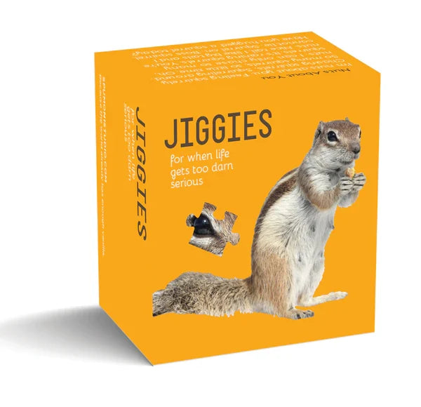 A bright yellow Jiggies puzzle box featuring a photo of a squirrel, with one eye shaped like a jigsaw piece. On the left, “JIGGIES” appears in large, thin black letters, with the tagline “for when life gets too darn serious” printed beneath.