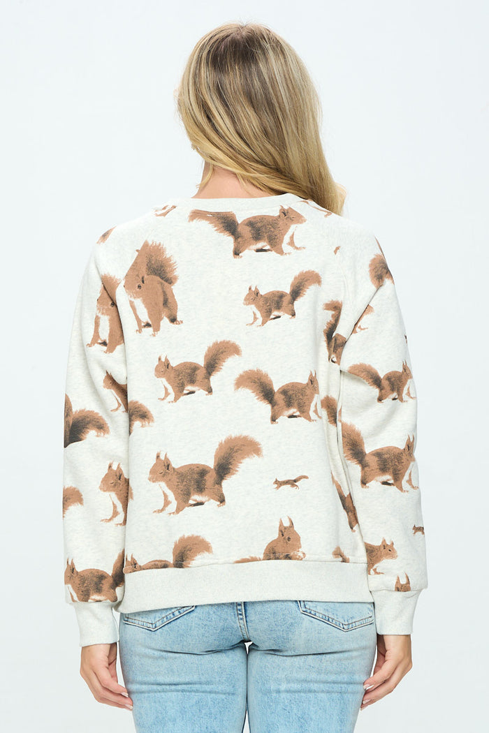 The back view shows an off‑white, cozy cotton‑blend sweatshirt worn by a model. The fabric is smooth and soft, featuring a flat, all‑over printed pattern of small brown and white squirrels in playful poses. The sweatshirt has a classic crew neckline and a slightly cropped, relaxed fit designed for comfortable everyday wear.