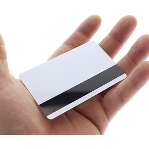 A hand holding a blank white Standard CR80 30mil Card w/ HiCo Mag Stripe on one side, made from high-quality PVC. Sold by Specialist ID.