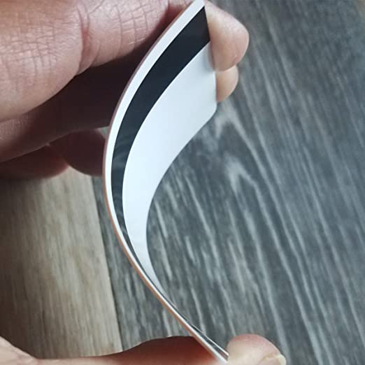 A close-up photo of a hand holding a flexed piece of white paper with Standard CR80 30mil Cards w/ HiCo Mag Stripe. The background features a wooden surface. Sold by Specialist ID.