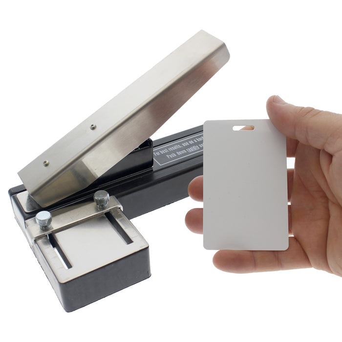 A hand holding a blank ID card next to a Stapler-Style Slot Punch With Adjustable Guide (P/N SPID-9750).