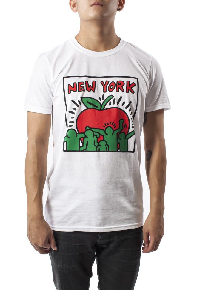 A man wears a soft white T‑shirt with a large Keith Haring–style apple graphic on the front. The apple has thick black outlines and is filled with bright red and green dancing figures. The shirt has short sleeves, a crew neck, and a classic unisex fit. It’s lightweight, comfortable, and available in sizes from small to extra large.