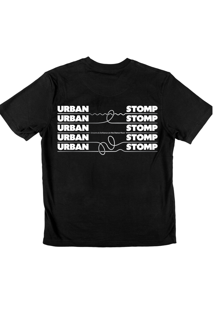 The shirt displays the word ‘URBAN’ in bold white block letters, connected by loose white squiggles to the word ‘STOMP,’ also in bold white caps. This paired design repeats five times across the chest against a black background.