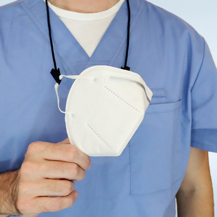 A person in light blue scrubs is holding a white face mask in their right hand, with the mask hanging from a USA Made Adjustable Double Clip Lanyard - Woven Nylon Neck Hanger with 2 Bulldog Clips around their neck.