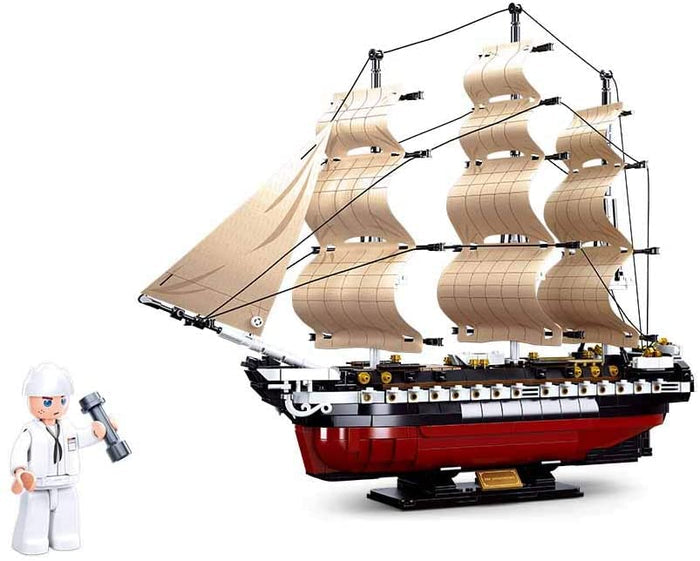 The USS Constitution 1794 Navy Frigate comes in a large, features a finished ship sailing on a white background, with three detailed masts, off-white sails, and a red-and-black textured hull.  A small illustration in the bottom left corner depicts a sailor holding a weight.