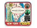 Overhead view of a small rectangular Cavallini & Co. keepsake tin with a hinged lid. The vintage-style design features a colorful collage in green, blue, cream, red and yellow, including the Statue of Liberty, a partial map of New York City, iconic landmarks, a yellow taxi, and classic city signs.