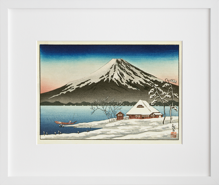 Winter landscape with small snow-covered building on the coast and view of Mount Fuji